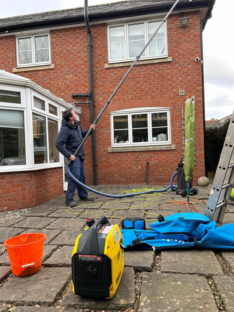 A man cleaning the gutters of a house