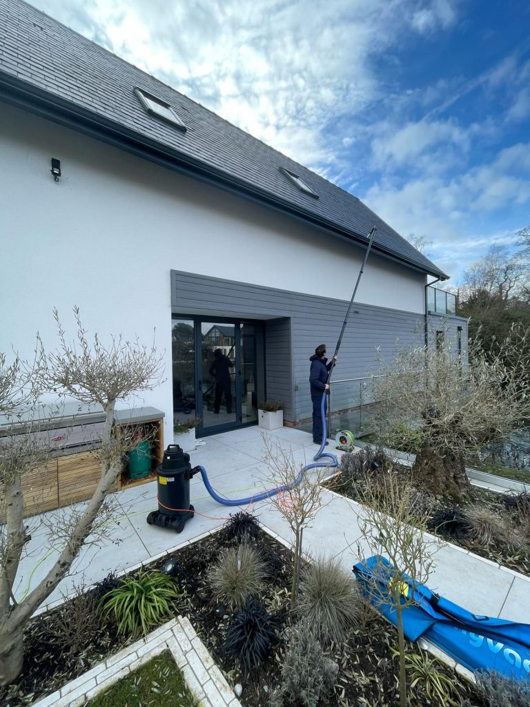 A man cleaning the gutters using a gutter vac