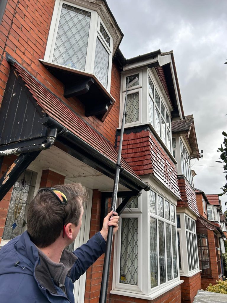 A man cleaning windows at the front of the house.