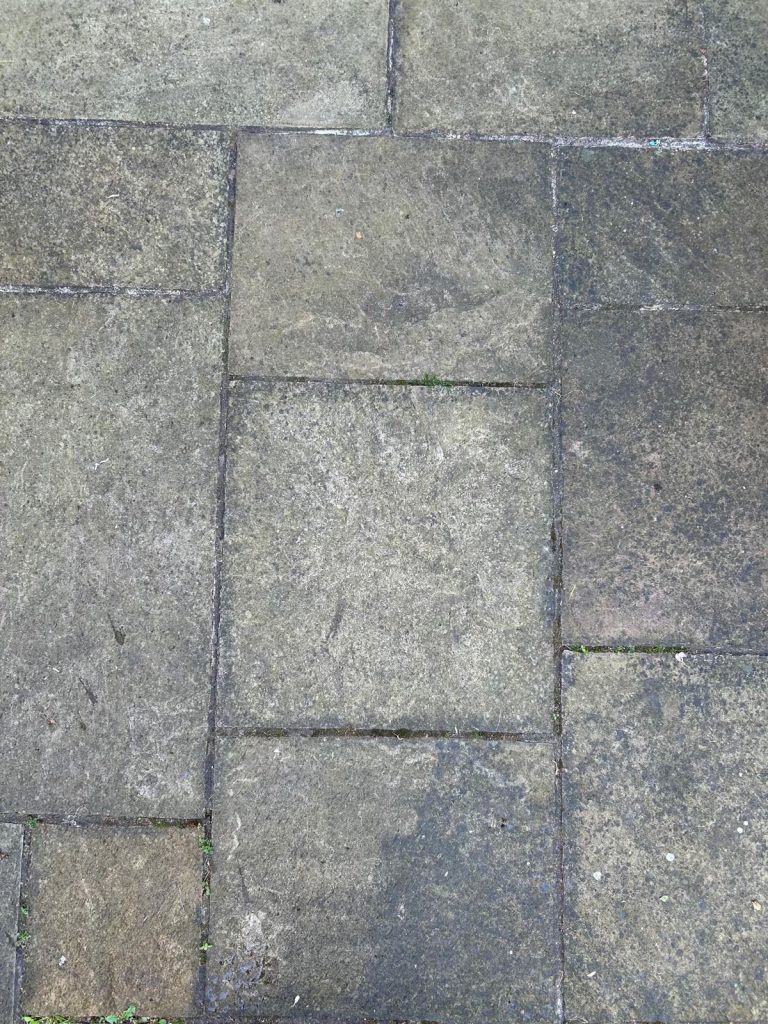 A picture of some patio slabs before being cleaned