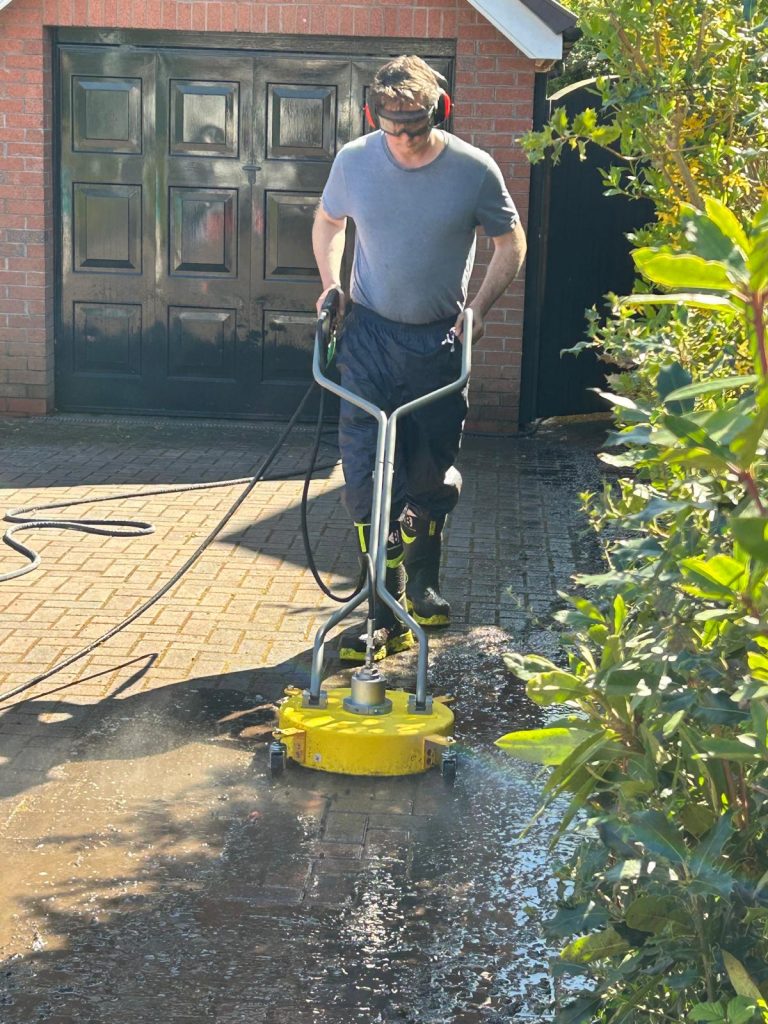 A man cleaning a driveway with a pressure washer.